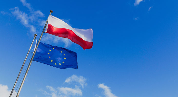 Die Polnische und die EU-Flagge vor einem blauen Himmel.