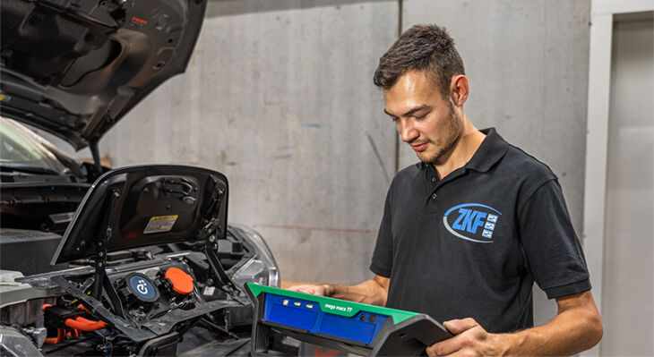 Junger Mann mit Diagnoseinstrument an einem Auto