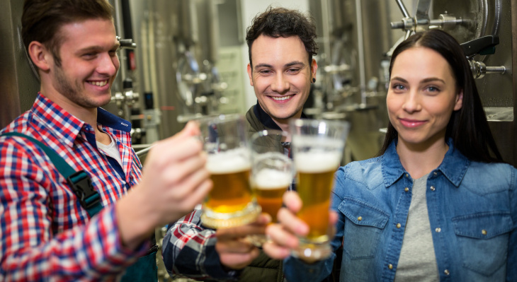 Junge Bierbrauer stoßen in der Brauerei auf das Bier an