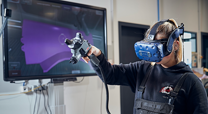 Eine Auszubildende im Kfz-Handwerk arbeitet mit einem VR-Farbspritz-Simulator.