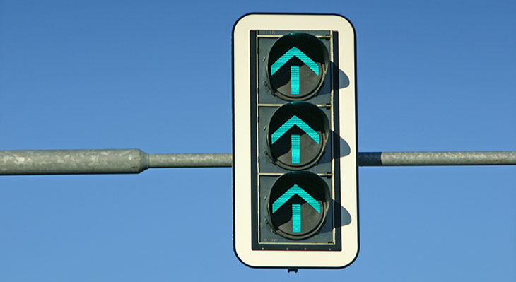 Eine Ampel mit drei grünen Pfeilen, die nach oben zeigen.