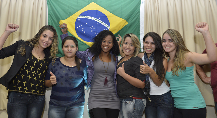 6 junge Frauen stehen in Siegerinnen-Pose vor brasilianischer Flagge